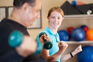 A therapist helping a man lift weights