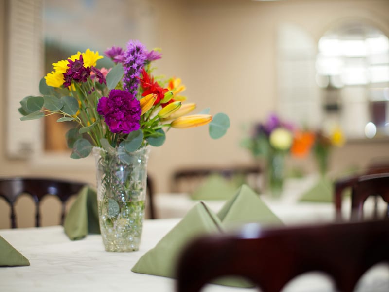 A vase of flowers on a table in the dining room at Mckinley Park