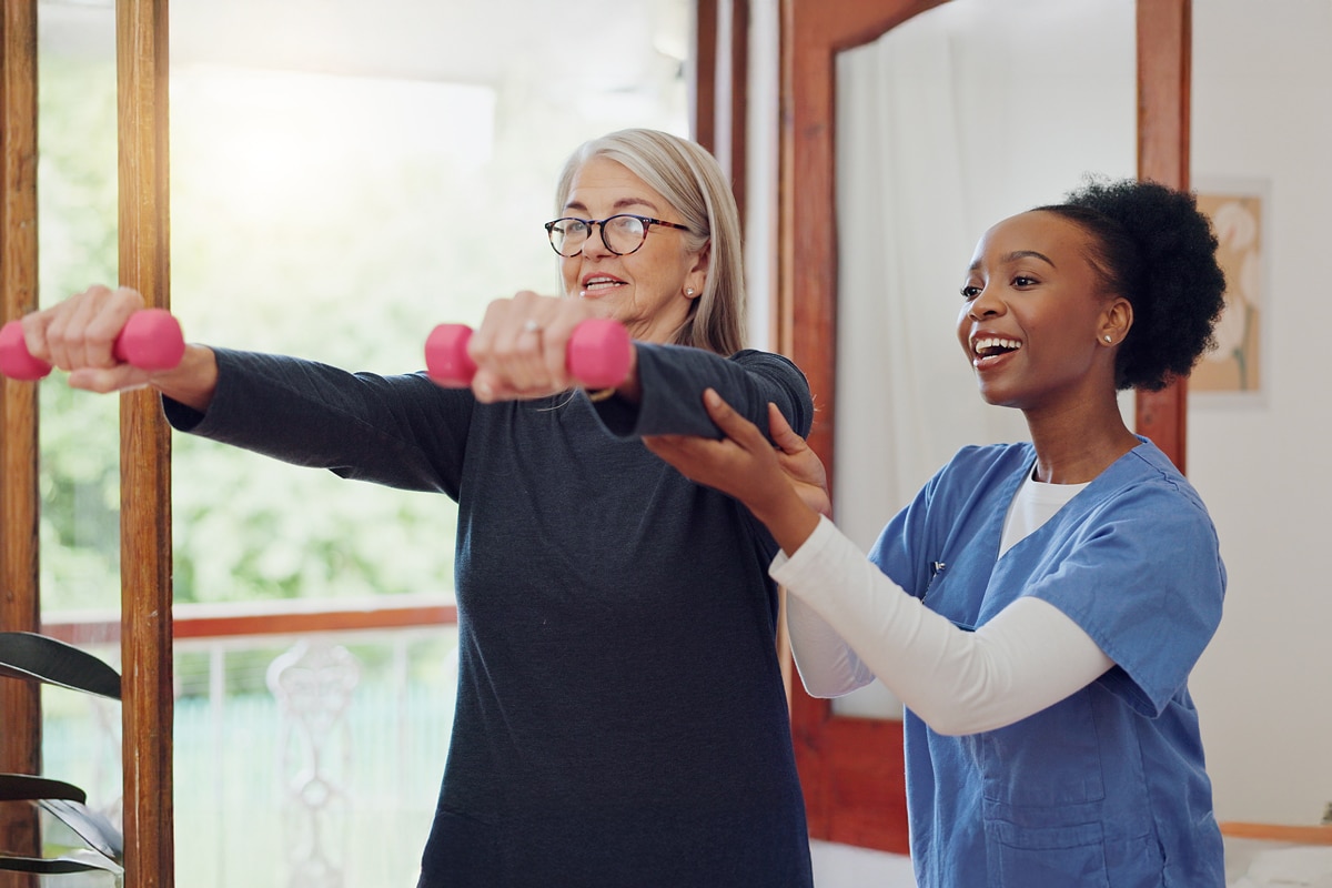 post acute rehabilitation specialist helping senior with weights